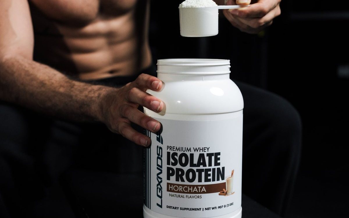 A scoop of LGXNDS whey isolate protein over the tub